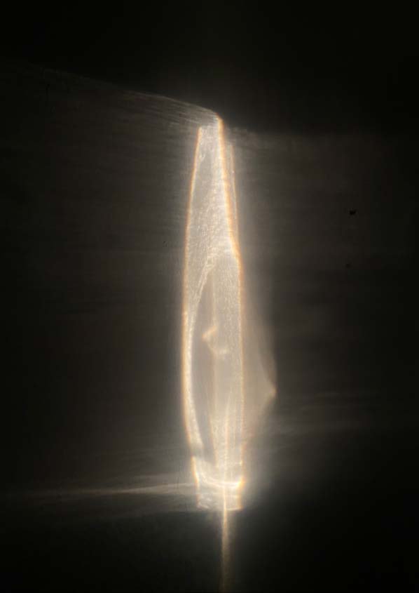 A vertical blade of light, refracted through water and glass.
