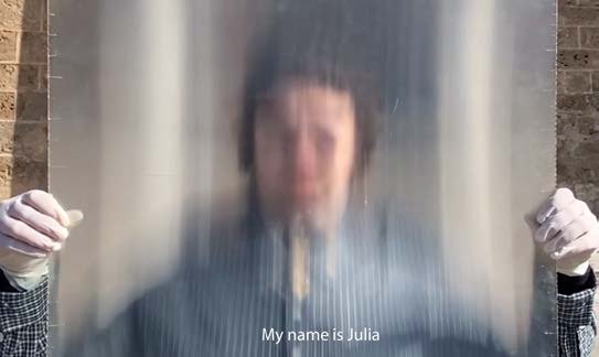 A blurred figure behind a curtain, subtitled “My name is Julia”.